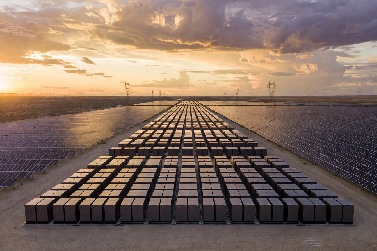 Massive Tesla Megapack battery installation glowing at twilight next to a vast solar farm