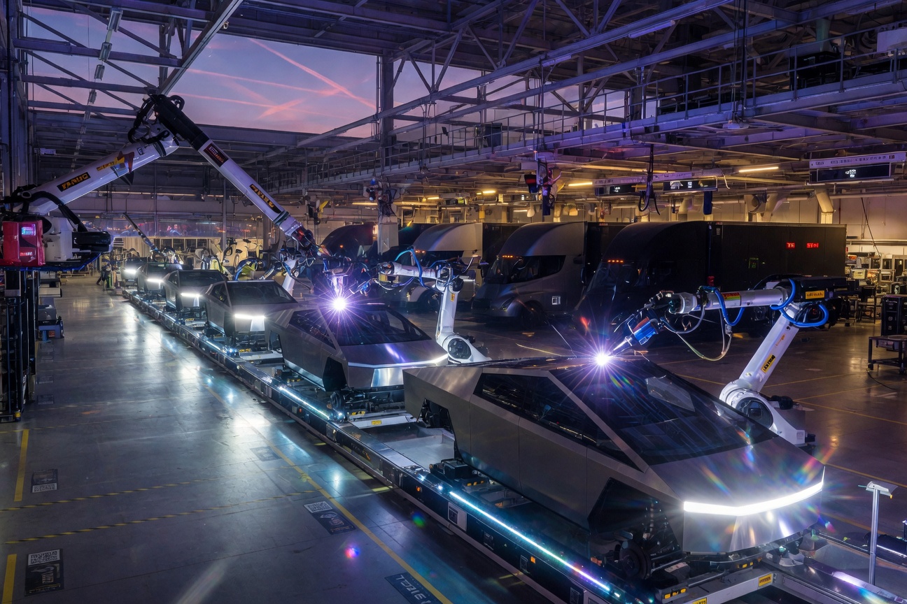 Futuristic Tesla Cybertruck and Semi trucks lined up at an automated gigafactory with robotic arms assembling vehicles under glowing blue lights