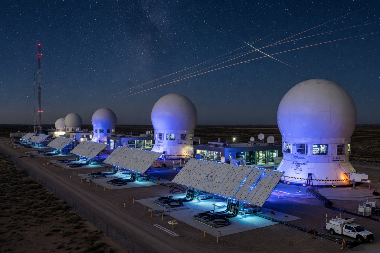 Futuristic satellite ground station with phased-array antenna arrays glowing under a starlit sky